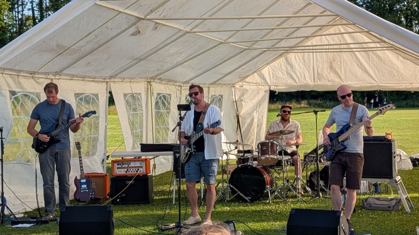 The four of us playing an outdoor gig under a marquee