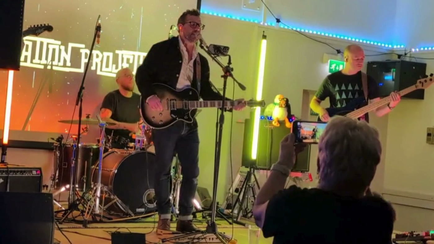 Restoration Project playing live, the band name projected behind the singer